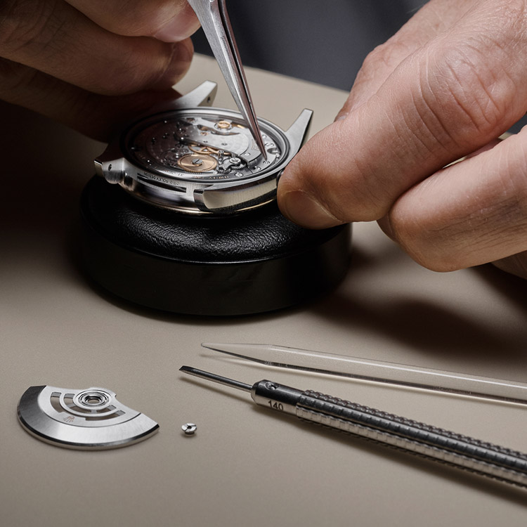 Ein Uhrmacher zerlegt das Werk einer Rolex Uhr in seine Kleinteile